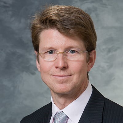 A headshot of Dr. James Maloney wearing a black suit and light blue tie.