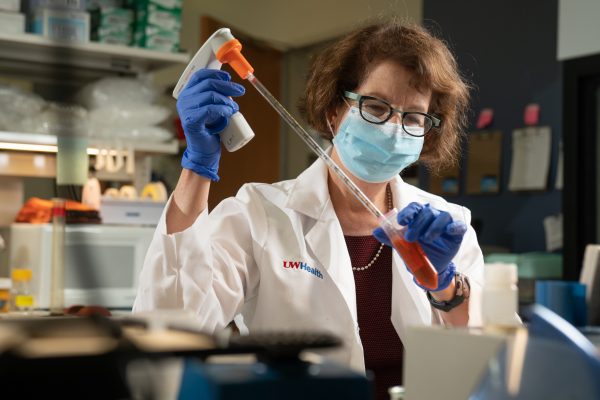 Dr. Lynn Schnapp pipetting a solution from a test tube in a research lab.